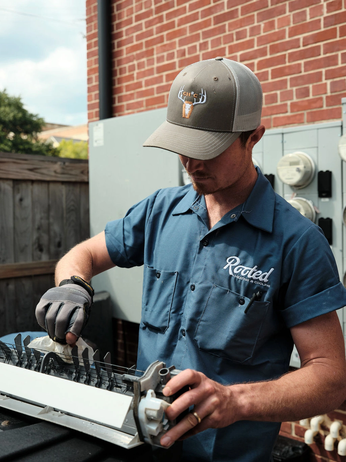 Rooted Heating & Air technician working on an outdoor AC coil